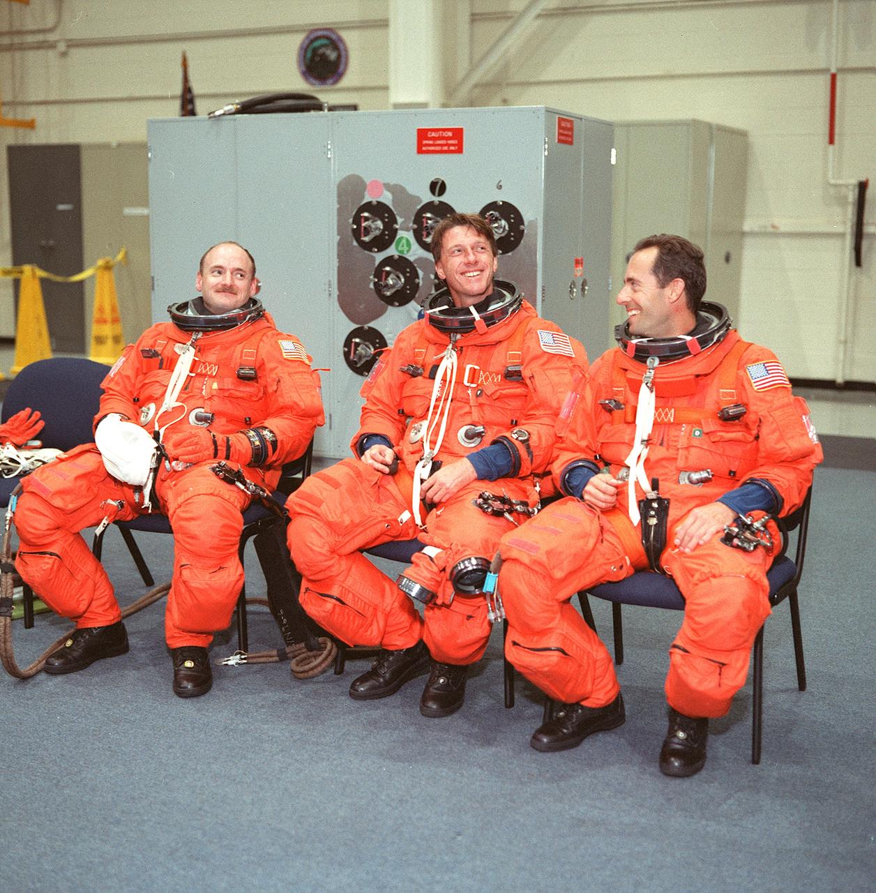 S99-08674 (24 May 1999) --- Three members of the third HST servicing mission's crew share a light moment while waiting to participate in emergency bailout training in the Johnson Space Center's Systems Integration Facility. From the left are astronauts Scott J. Kelly, C. Michael Foale and Jean-Francois Clervoy. Clervoy is a mission specialist representing the European Space Agency (ESA); Foale is a mission specialist; and Kelly, the STS-103 pilot.