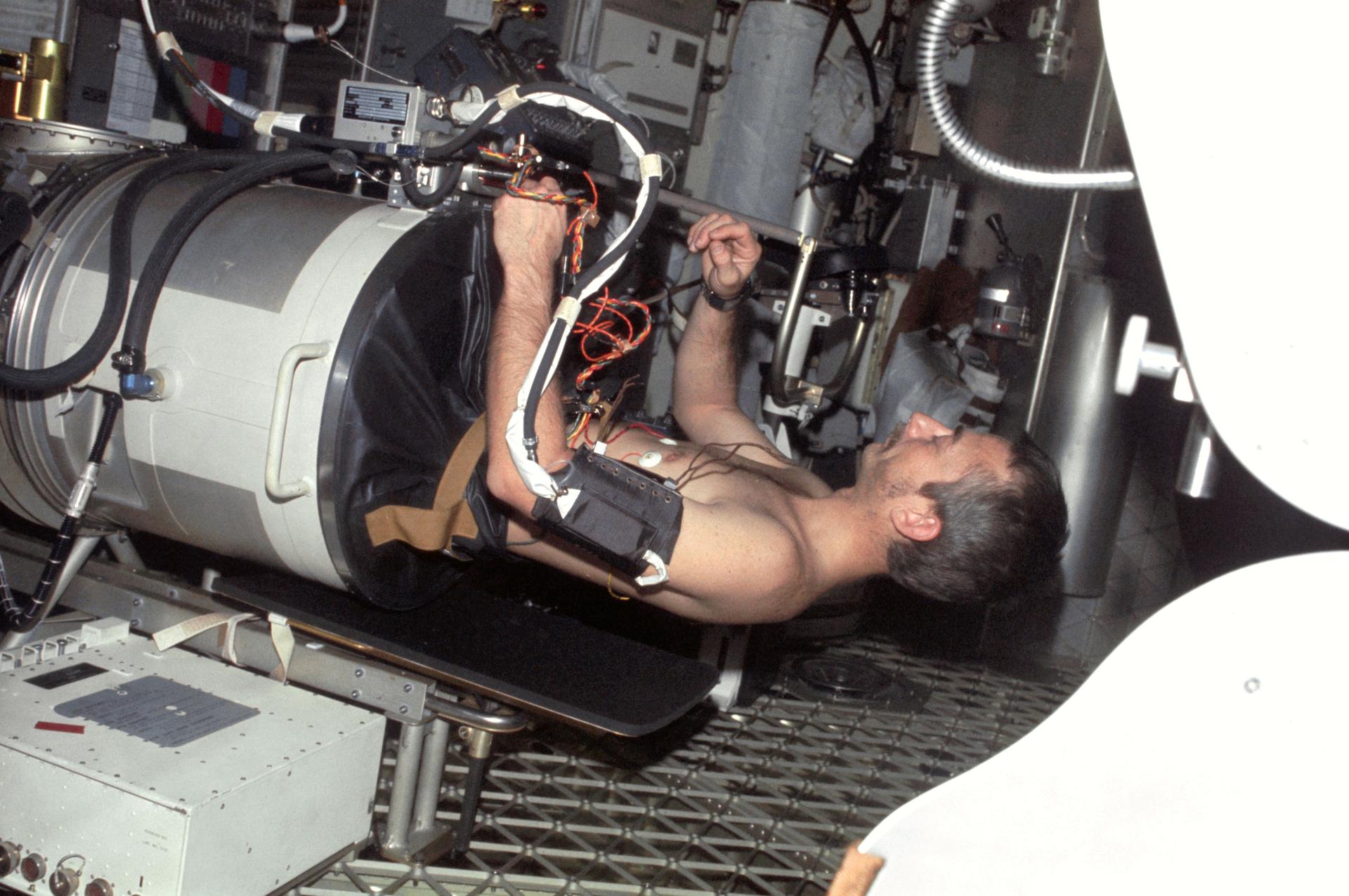 Astronaut Owen Garriott lies in Lower Body Negative Pressure Device on board the Skylab space station in August 1973.