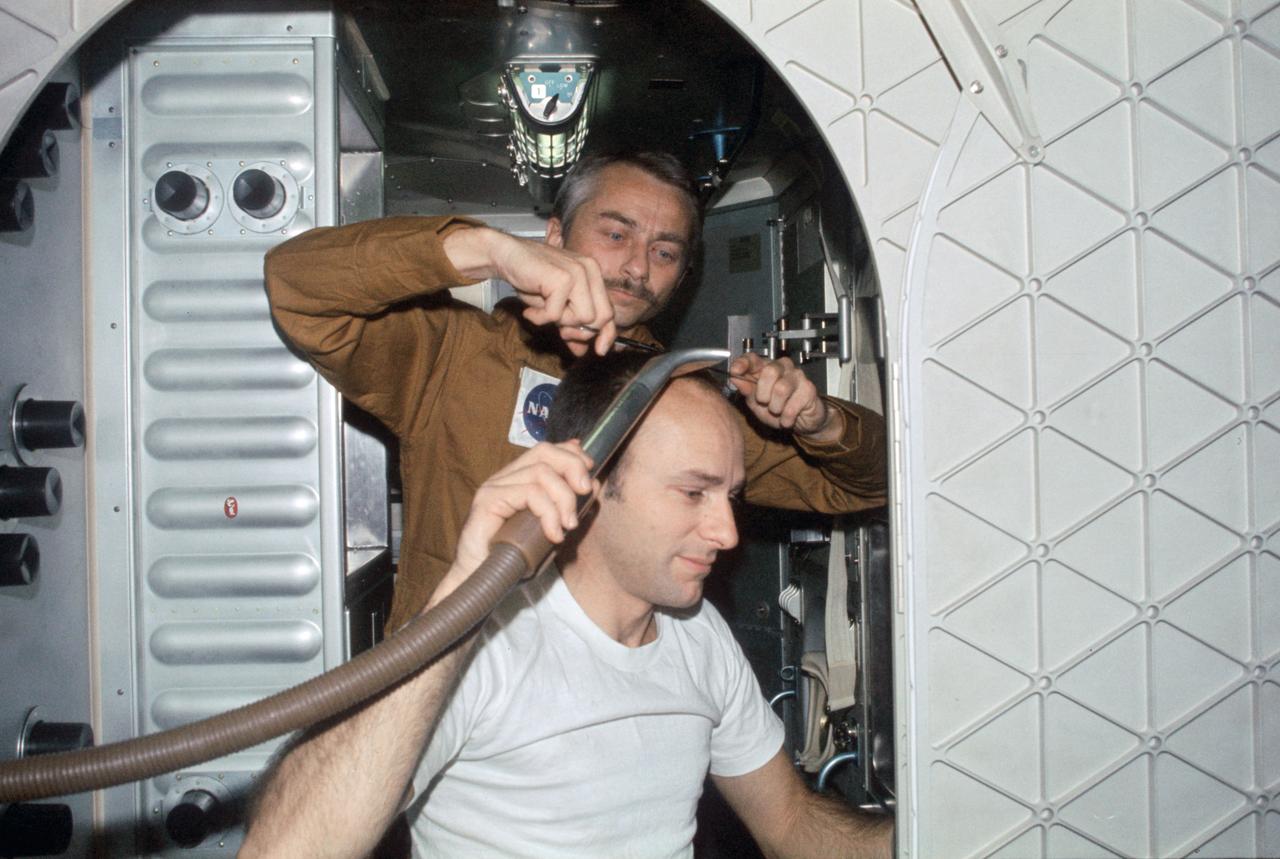 SL3-108-1292 (19 Aug. 1973) --- Scientist-astronaut Owen K. Garriott, Skylab 3 science pilot, trims the hair of astronaut Alan L. Bean, commander, in this onboard photograph from the Skylab Orbital Workshop (OWS) in Earth orbit. Astronaut Jack R. Lousma, pilot, took this picture with a 35mm Nikon camera.  Bean holds a vacuum hose to gather in loose hair. The crew of the second manned Skylab flight went on to successfully complete 59 days aboard the Skylab space station cluster in Earth orbit. Photo credit: NASA
