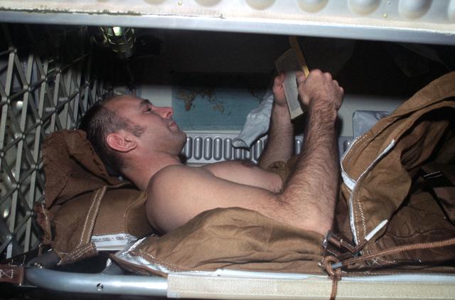 NASA image: View of Astronaut Alan Bean in sleep compartment, reading a book