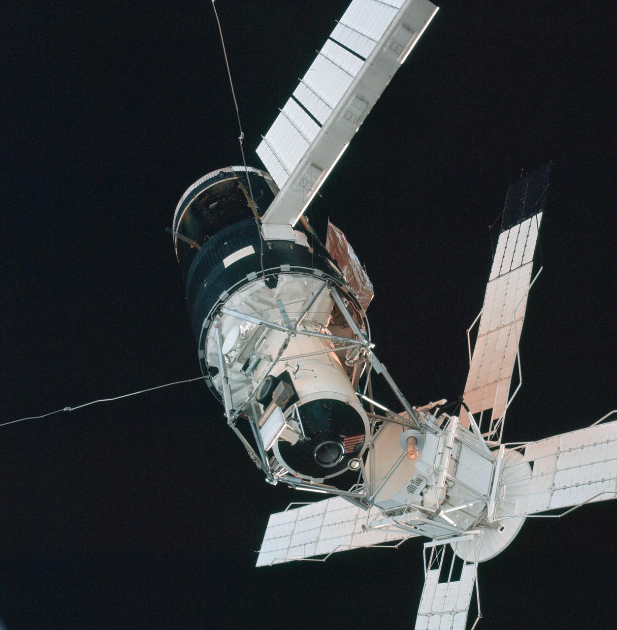 A close-up view of the Skylab space station cluster photographed against a black sky background from the Skylab 3 command module during the "fly around" inspection prior to docking. Note the one solar array system wing on the Orbital Workshop (OWS) which was successfully deployed during EVA on the first manned Skylab mission. The primary docking part at the forward end of the Multiple Docking Adapter (MDA) is visible below the Apollo Telescope Mount (ATM).
