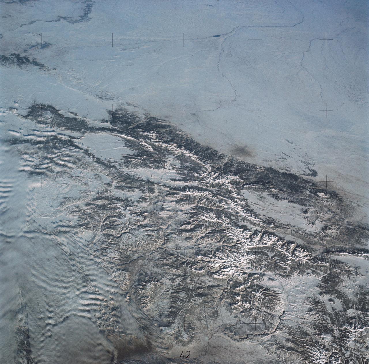 SL4-138-3875 (February 1974) --- A color oblique photograph looking east over the Rocky Mountains and Great Plains. This view covers a portion of the States of Colorado, Wyoming, and Nebraska. A Skylab 4 crewmen took this picture with a hand-held 70mm Hasselblad camera. This entire region, covered with a blanket of snow, depicts much of the structural and topographic features of the Rocky Mountain chain. Man's only apparent change to the snow pattern seen here is the (right center) metropolitan areas of Denver and Colorado Springs, Colorado, which can be observed along the eastern edge of the mountain front. Grand Junction, Colorado on the western slope of the Rocky Mountains is just off the photograph at left center bottom. The major inter-montane valleys of South Park (right center), Middle Park (center), and North Park (left center) are clearly visible and separate the Colorado Rockies Front Range from the high rugged mountains can be discovered such as Pikes Peak near right border (center), Mt. Cunnison region, circular feature accentuated by the Cunnison River (dark) in the right center (bottom) of the photograph. The snow covered peaks of Mts. Harvard, Princeton and Yale form the high region of the Collegiate Range which is the pronounced mountain area in the right center. Snow cover not only enhances mountain features but also the drainage patterns. East of Denver (right corner) the sinuous trace of the South Platte River (center) and its junction with the North Platte River near North Platte, Nebraska. Lake McConaughy in Nebraska is the body of water (black) near the river intersection. The trace of the Republic River in southern Nebraska is visible near the right corner of the photography. Geologic and hydro logic studies using this photograph will be conducted by Dr. Roger Morrison, U.S. Geological Survey. Photo credit: NASA