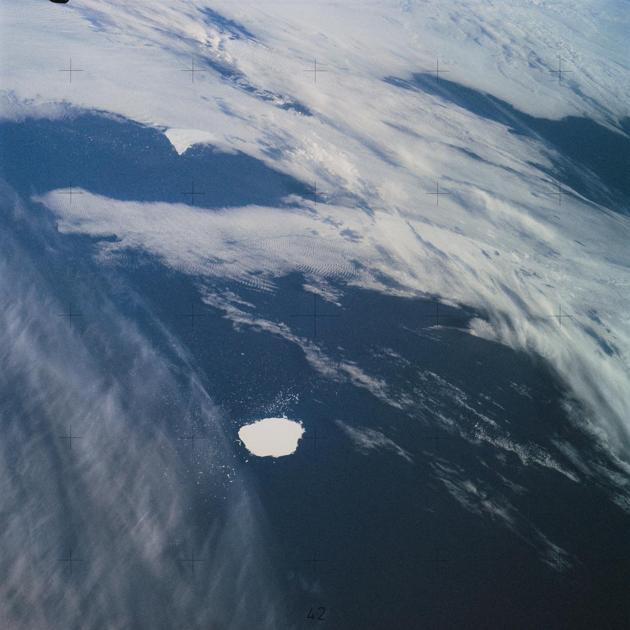 SL4-142-4577 (28 Jan. 1974) --- Two large ice islands in the vicinity of South Georgia Island in the South Atlantic Ocean, as photographed from the Skylab space station in Earth orbit by one of the Skylab 4 crewmen. The camera used was a hand-held 70mm Hasselblad, with SO-368 medium-speed Ektachrome. One of the ice islands is partially obscured by clouds. Ice islands were observed as large as 45 by 60 kilometers (27 x 37 miles) and as far north as 45 degrees south latitude. The size and distribution of the "small" icebergs (to a ship they would look very large) can be used to study the local winds and currents. Recent research has suggested the possibility of towing such Antarctic icebergs to selected areas and using them as water supplies. One such iceberg would contain many times the water as in Lake Powell. Photo credit: NASA
