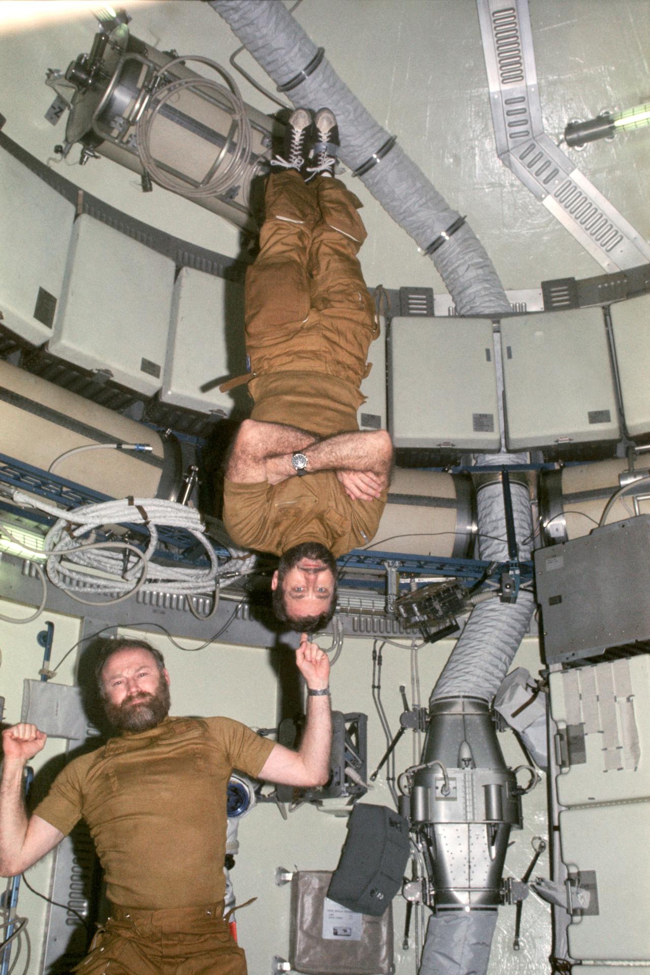 Astronauts Carr and Pogue in the Orbital Workstation. Carr appears to be balancing Pogue on one finger while pogue is upside down.