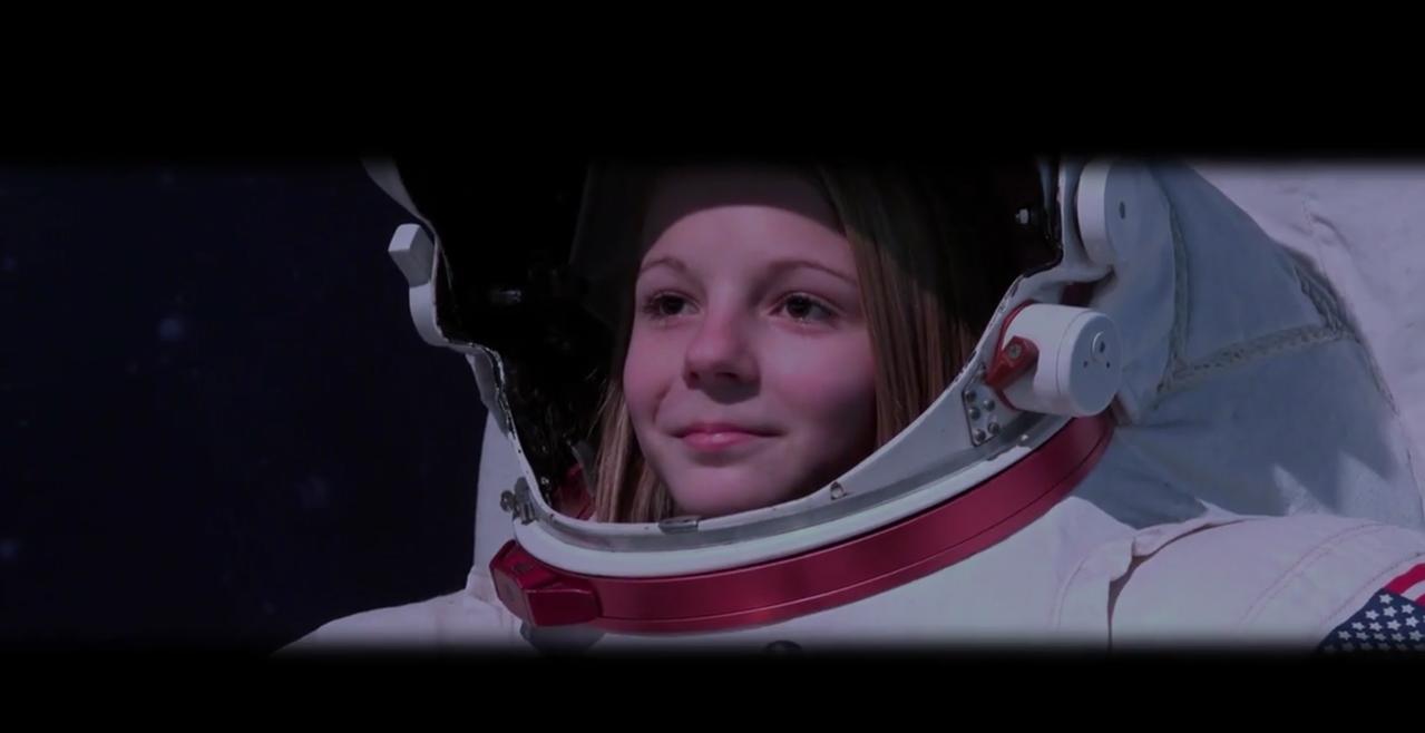 Young girl in astronaut suit, looking out into space.