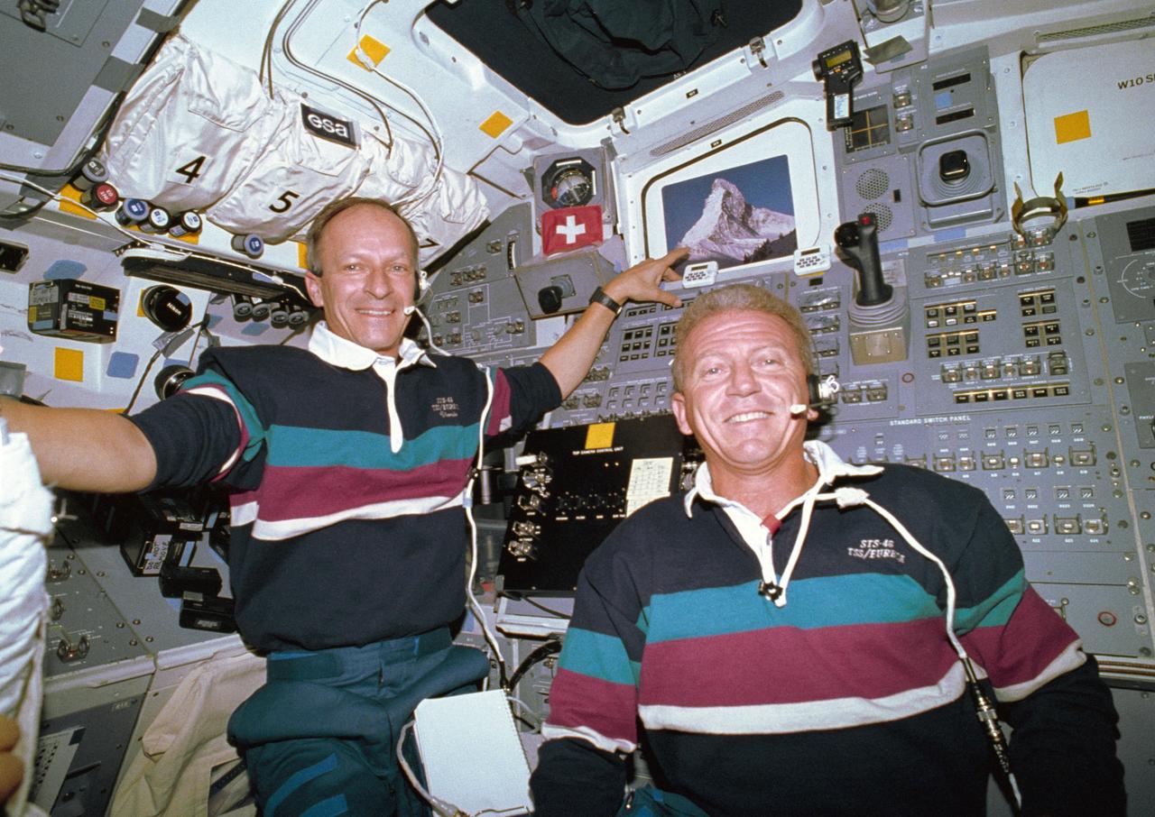 STS046-03-020 (7 Aug 1992) --- With their windows boarded up for specific intravehicular operations, two crew members pose for an in-space portrait.  At left, Swiss scientist Claude Nicollier, representing the European Space Agency (ESA), steadies himself near a tiny Swiss flag and a photograph of the Matterhorn, a popular peak on the Swiss-Italian border.  Astronaut Loren J. Shriver (right) served as mission commander for the eight-day flight.