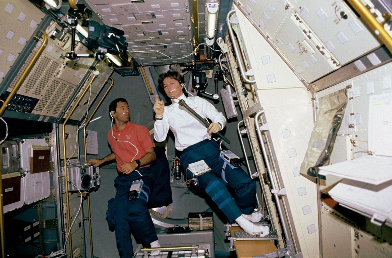 View showing Payload Specialists Bonnie Dunbar and Larry DeLucas in the aft section of the U. S. Microgravity Laboratory-1. Dunbar prepares to load a sample in the Crystal Growth Furnace (CGF) Integrated Furnace Experiment Assembly (IFEA) in rack 9 of the Microgravity Laboratory, while DeLucas checks out the multi-purpose Glovebox Facility.