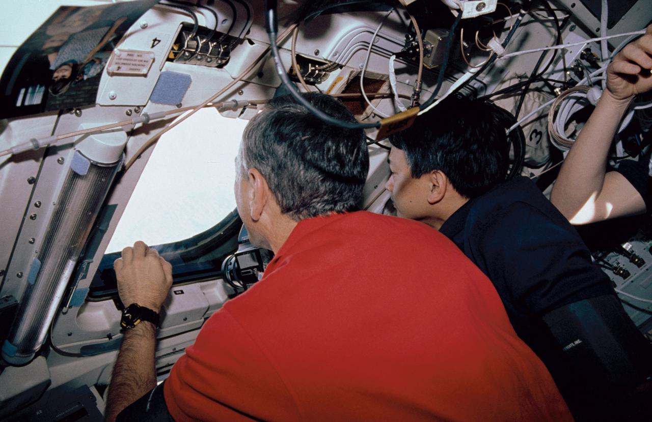 STS050-06-011 (25 June-9 July 1992) --- Astronaut Carl J. Meade (left), mission specialist, and Eugene H. Trinh, payload specialist, share a view through one of the Space Shuttle Columbia's aft flight deck windows during a break in photography of Earth.  The two were among seven crew members who shared 14 record-setting days aboard the Space Shuttle supporting the United States Microgravity Laboratory (USML-1) mission.