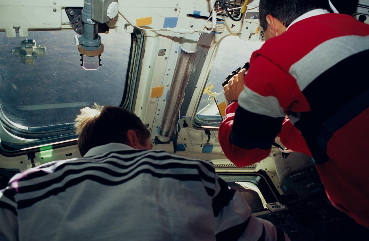 Astronauts Frank L. Culbertson Jr., STS-51 mission commander, and Daniel W. Bursch, mission specialist, are seen on Discovery's flight deck. The two were supporting operations free-flying Orbiting and Retrievable Far and Extreme Ultraviolet Spectrometer (ORFEUS) and its Shuttle Pallet Satellite (SPAS), pictured through the left window.
