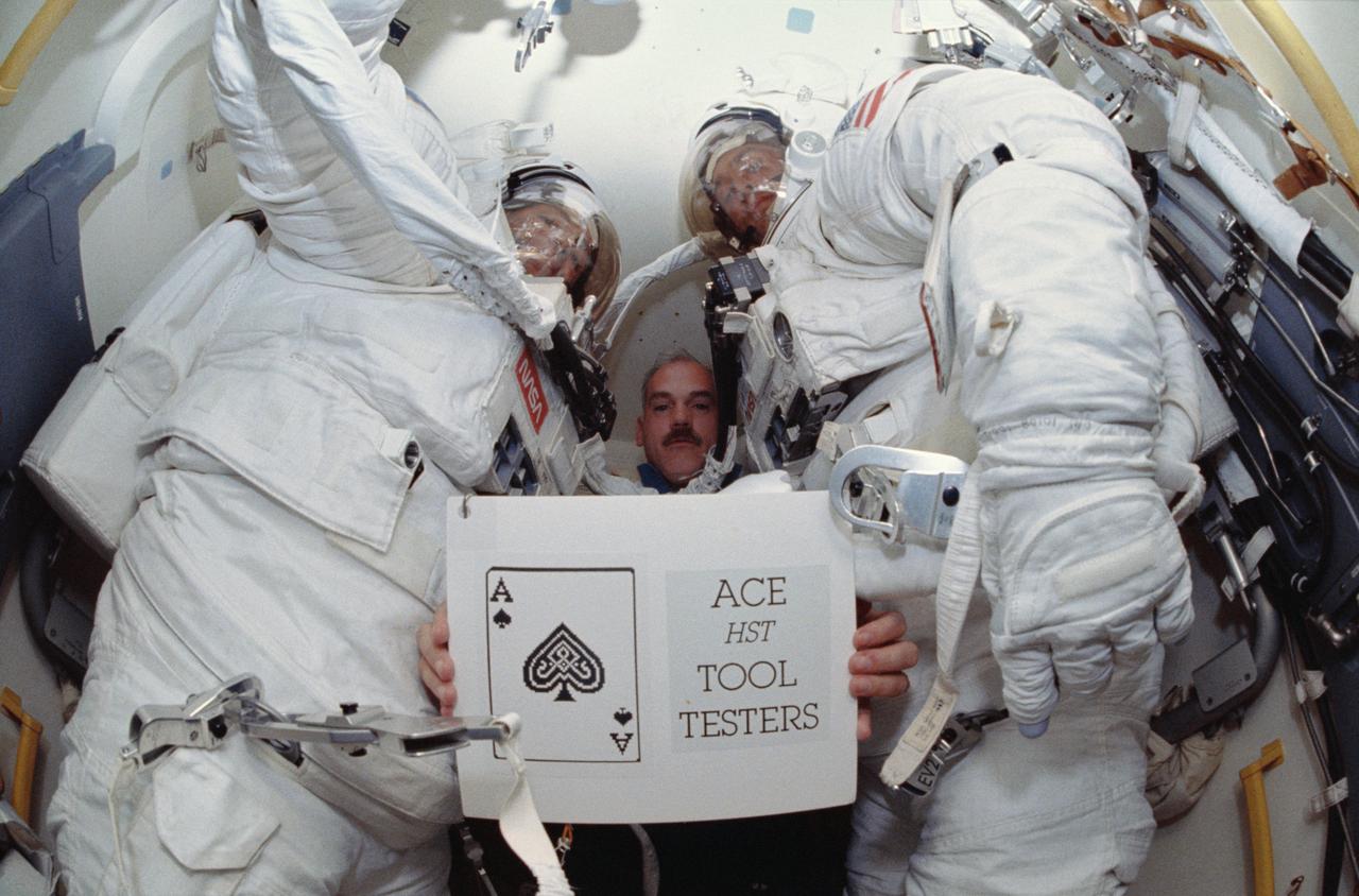 STS051-66-009 (16 Sept 1993) --- In Discovery's airlock, astronaut William F. Readdy, pilot, holds up a STS-51 slogan -- "Ace HST Tool Testers" -- for still and video cameras to record. Readdy is flanked by astronauts Carl E. Walz (left) and James H. Newman, who had just shared a lengthy period of extravehicular activity (EVA) in and around Discovery's cargo bay. Not pictured are astronauts Frank L. Culbertson Jr., mission commander, and Daniel W. Bursch, mission specialist.