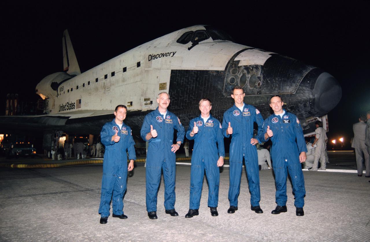 STS051-S-161 (22 Sept 1993) --- Thumbs up from all five crew members signal the successful completion of almost ten full days in space.  Backdropped against Discovery -- their in-space "home" for the flight -- are, left to right, astronauts Daniel W. Bursch, William F. Readdy, Frank L. Culbertson Jr., James H. Newman and Carl E. Walz.