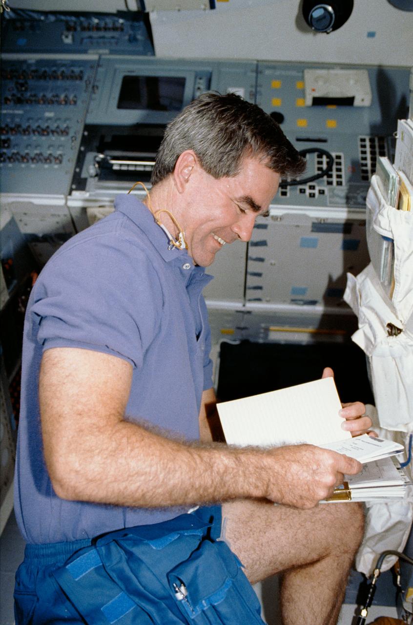 Mission Specialist Lacy Veach in the aft flight deck reviewing a procedures manual.