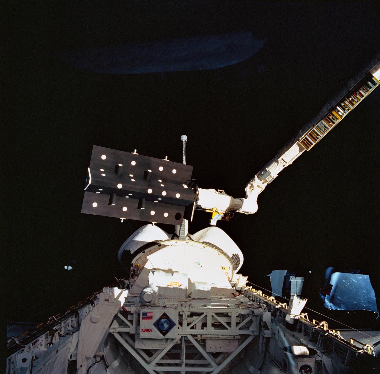 STS052-71-057 (22 Oct-1 Nov 1992) --- This 70mm frame, photographed with a handheld Hasselblad camera aimed through Columbia's aft flight deck windows, captures the operation of the Space Vision System (SVS) experiment above the cargo bay.  Target dots have been placed on the Canadian Target Assembly (CTA), a small satellite, in the grasp of the Canadian-built remote manipulator system (RMS) arm.  SVS utilized a Shuttle TV camera to monitor the dots strategically arranged on the satellite, to be tracked.  As the satellite moved via the arm, the SVS computer measured the changing position of the dots and provided real-time television display of the location and orientation of the CTA.  This type of displayed information is expected to help an operator guide the RMS or the Mobile Servicing System (MSS) of the future when berthing or deploying satellites. Also visible in the frame is the U.S. Microgravity Payload (USMP-01).
