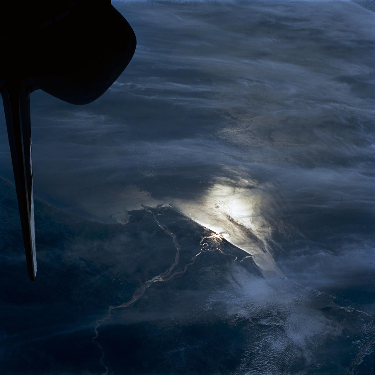 STS054-80-024 (13-19 Jan 1993) --- As the Shuttle was passing southeast over the coast of India, approaching the Bay of Bengal, Endeavour's crew took this picture of the Godavari River Delta.  The sun glint pattern was centered directly over the delta and highlighted well the intricate drainage pattern.  Offshore, water features associated with current boundaries and river plumes are readily visible.  The line of clouds along the coast south of the delta suggest that surface winds are blowing onshore from the Bay of Bengal.  As the air passes over the warmer coastal water and land, it is warmed and begins to rise.  The moisture in the air condenses, forming a line of low-level clouds.