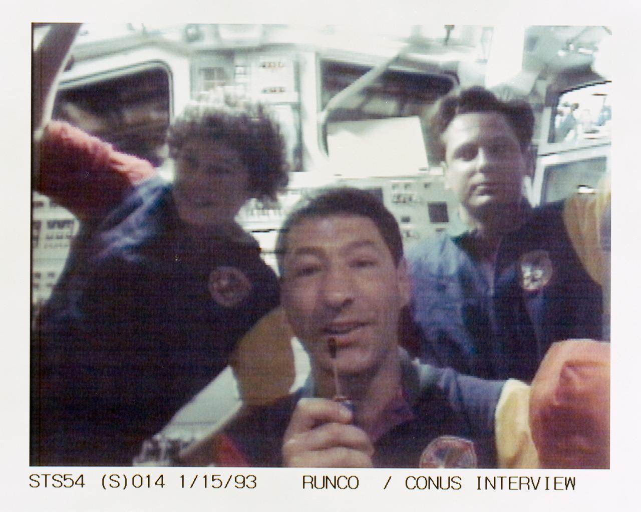 STS054-S-014 (15 Jan 1993) --- Runco talks to a radio station from the flight deck of Endeavour while, in the background, several crewmates await their turns to communicate with other stations. The scene was recorded at 13:48:45:11 GMT, Jan. 15, 1993.