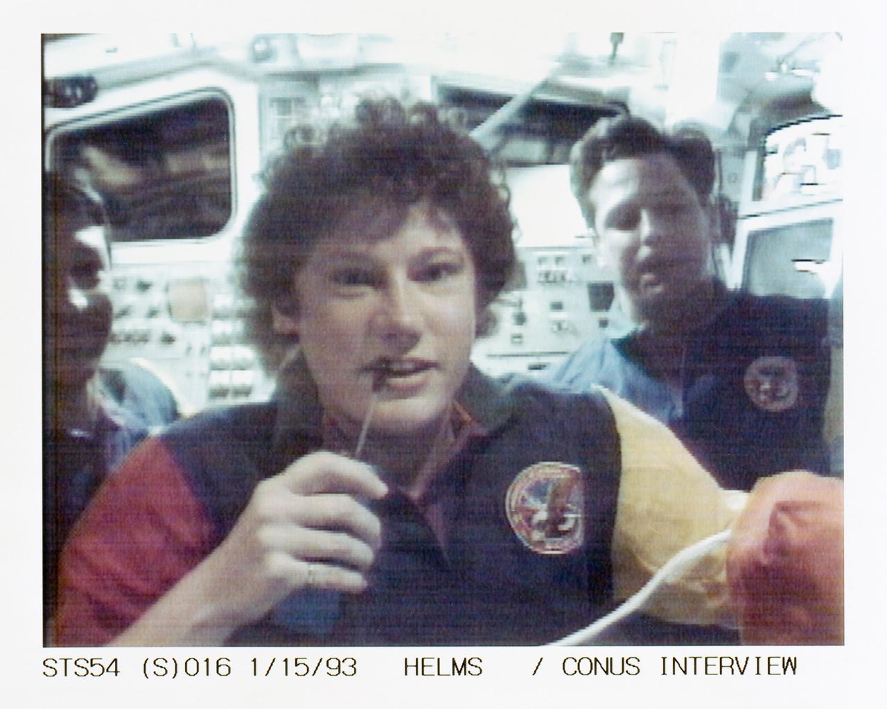 STS054-S-016 (15 Jan 1993) --- Helms talks to a radio station from the flight deck of Endeavour while Runco, left, and Harbaugh look on in the background. The scene was recorded at 13:54:14:13 GMT, Jan. 15, 1993.