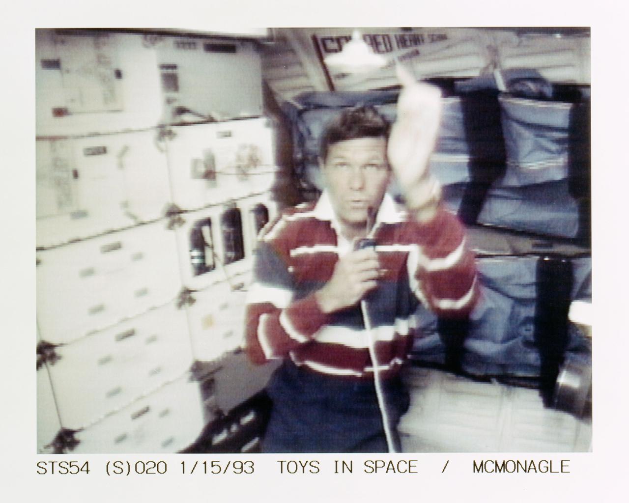 STS054-S-020 (15 Jan 1993) --- McMonagle watches as a top spins above his head on the middeck of the Earth-orbiting Endeavour.  The demonstration was part of a lengthy "physics of toys" program conducted by all five crewmembers on their third day aboard the Shuttle.  Through telephone and TV downlinks, students in four schools around the country participated in a special lesson to discover how specific toys function differently in the classroom compared to those on the Shuttle.  Students at Westwood Elementary School in Flint, Michigan -- McMonagle's hometown -- asked him questions about the several toys he demonstrated. The top demonstrates gyroscopic motion, the center of mass and angular momentum. The entire collection of toys will be videotaped for an educational program to be distributed to schools in the autumn. The scene was downlinked at 18:01:59:11 GMT, Jan. 15, 1993.