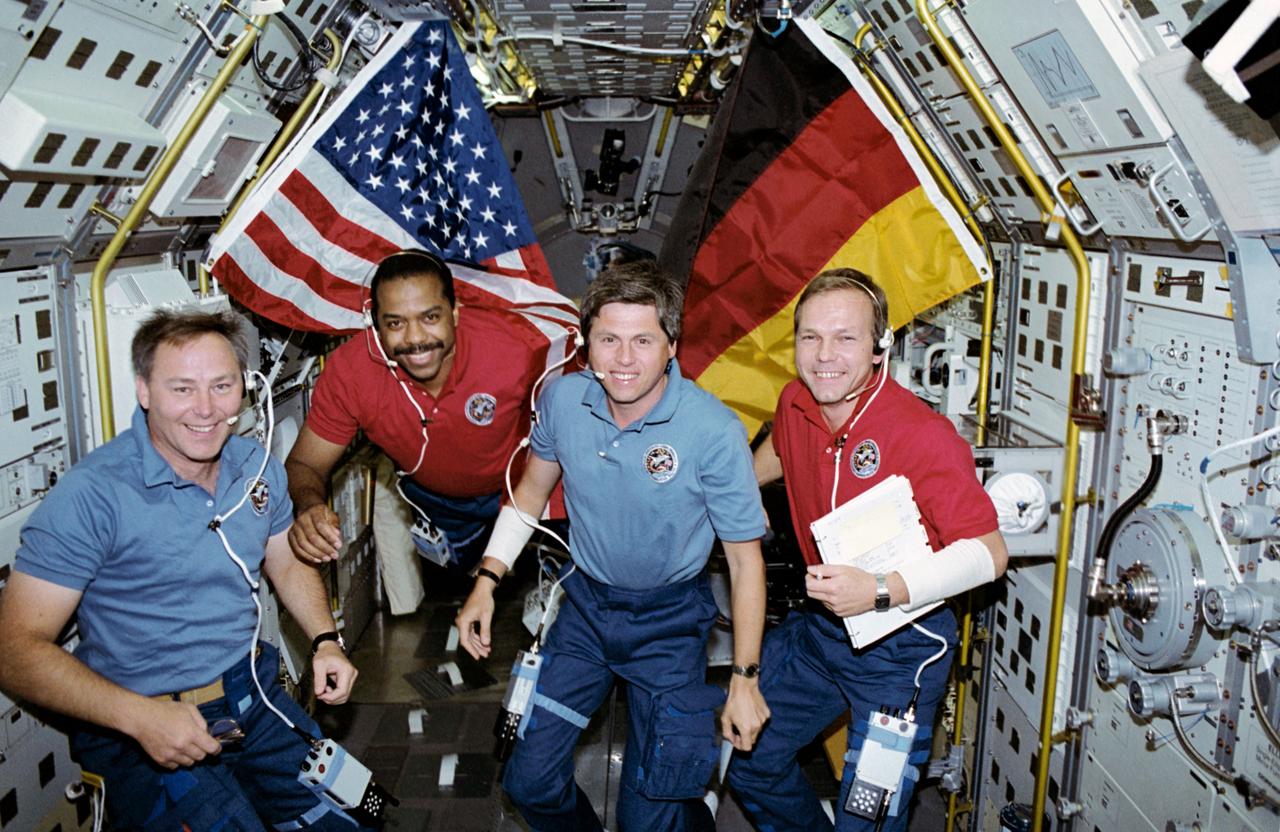 STS-55 crewmembers pose with United States and German flags inside the Spacelab Deutsche 2 (SL-D2) science module located in the payload bay (PLB) of Columbia, Orbiter Vehicle (OV) 102. Wearing communications kit assembly headsets (HDSTs) are (left to right) Mission Specialist 1 (MS1) and Payload Commander (PLC) Jerry L. Ross, MS3 Bernard A. Harris, Jr, German Payload Specialist 1 Ulrich Walter, and Payload Specialist 2 Hans Schlegel.