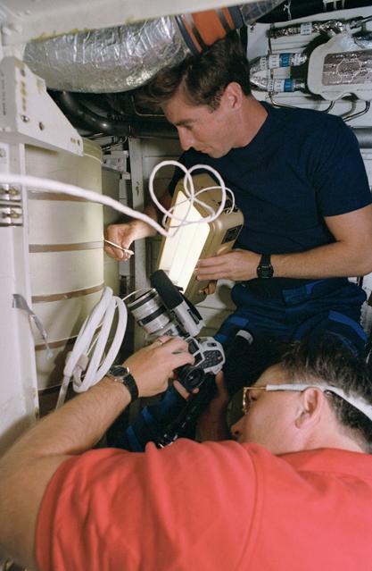 NASA image: STS-55 crewmembers repair waste water tank under OV-102's middeck subfloor