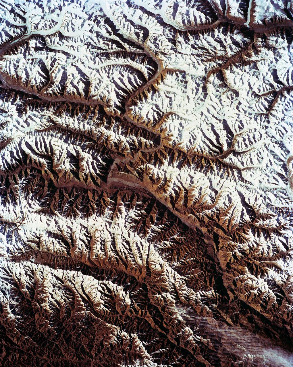 STS-56 Earth observation shows of some of the highest mountain peaks in the world taken from Discovery, Orbiter Vehicle (OV) 103, as it passed over India and China. The top of the view shows one of the snow and ice-covered massifs in the great Karakorum Range of north India. A star-shaped peak at top left reaches 23,850 feet. Glaciers can be seen in valleys at these high elevations. The international border between India to the south (top) and China (bottom) snakes left to right along a river near the top of the scene, then veers into the muntains at top left. Larger valleys, despite their elevation (all in excess of 14,000 feet), are occupied by transport routes joining points in India, China and the southern republics of the CIS. The ancient Silk Route between China and the Middle East lies not far to the north (outside the bottom of the frame).