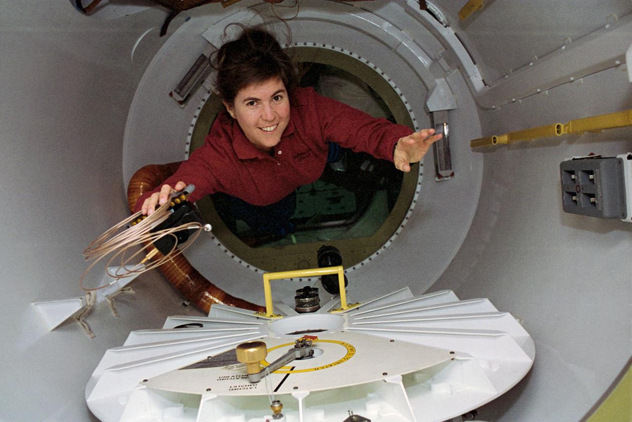 STS057-28-013 (21 June - 1 July 1993) --- With a camera and cable in hand, astronaut Janice E. Voss, mission specialist, floats through a special tunnel into the SpaceHab module.  Voss and five other NASA astronauts spent almost ten days aboard the Space Shuttle Endeavour in Earth-orbit supporting the SpaceHab mission, retrieving the European Retrievable Carrier (EURECA) and conducting various experiments.