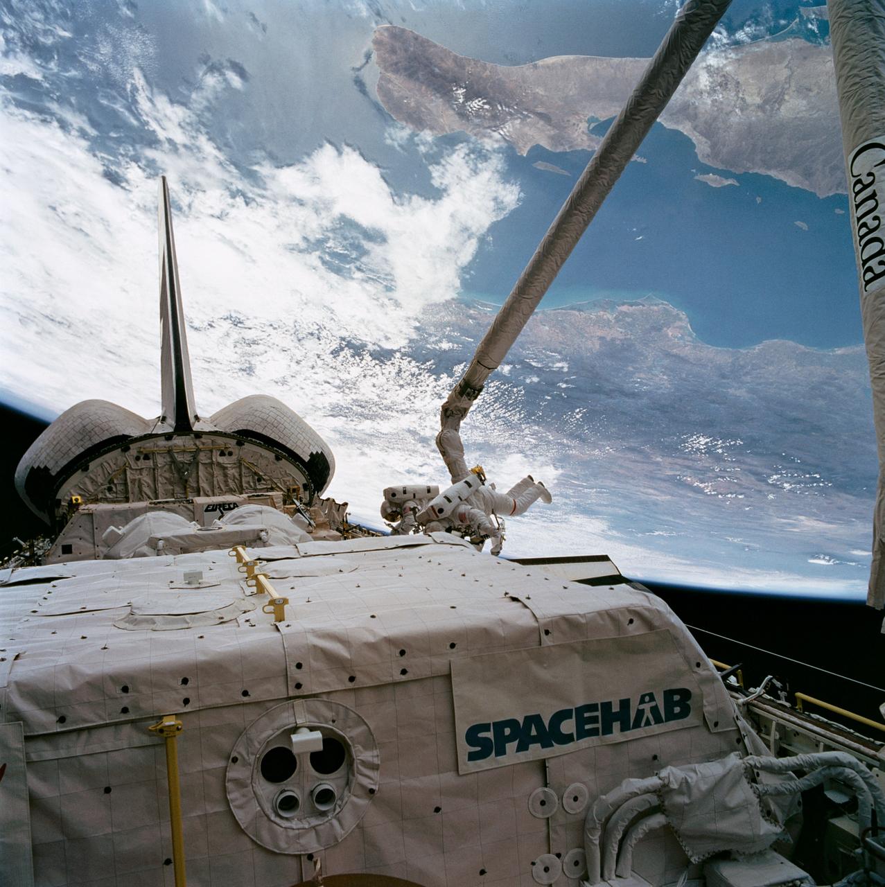 STS057-89-042 (24 June 1993) --- Baja California forms the backdrop for this extravehicular activity (EVA) scene captured on 70mm film by one of the STS-57 crew members in the Space Shuttle Endeavour's crew cabin.  Working near the recently "captured" European Retrievable Carrier (EURECA) at frame center are astronauts G. David Low (nearest camera) and Peter J. K. (Jeff) Wisoff.  Low is attached to a mobile foot restraint to the end of the Canadian-built Remote Manipulator System (RMS) arm.  The SPACEHAB module is seen in the foreground and EURECA is partially visible near Endeavour's aft firewall.