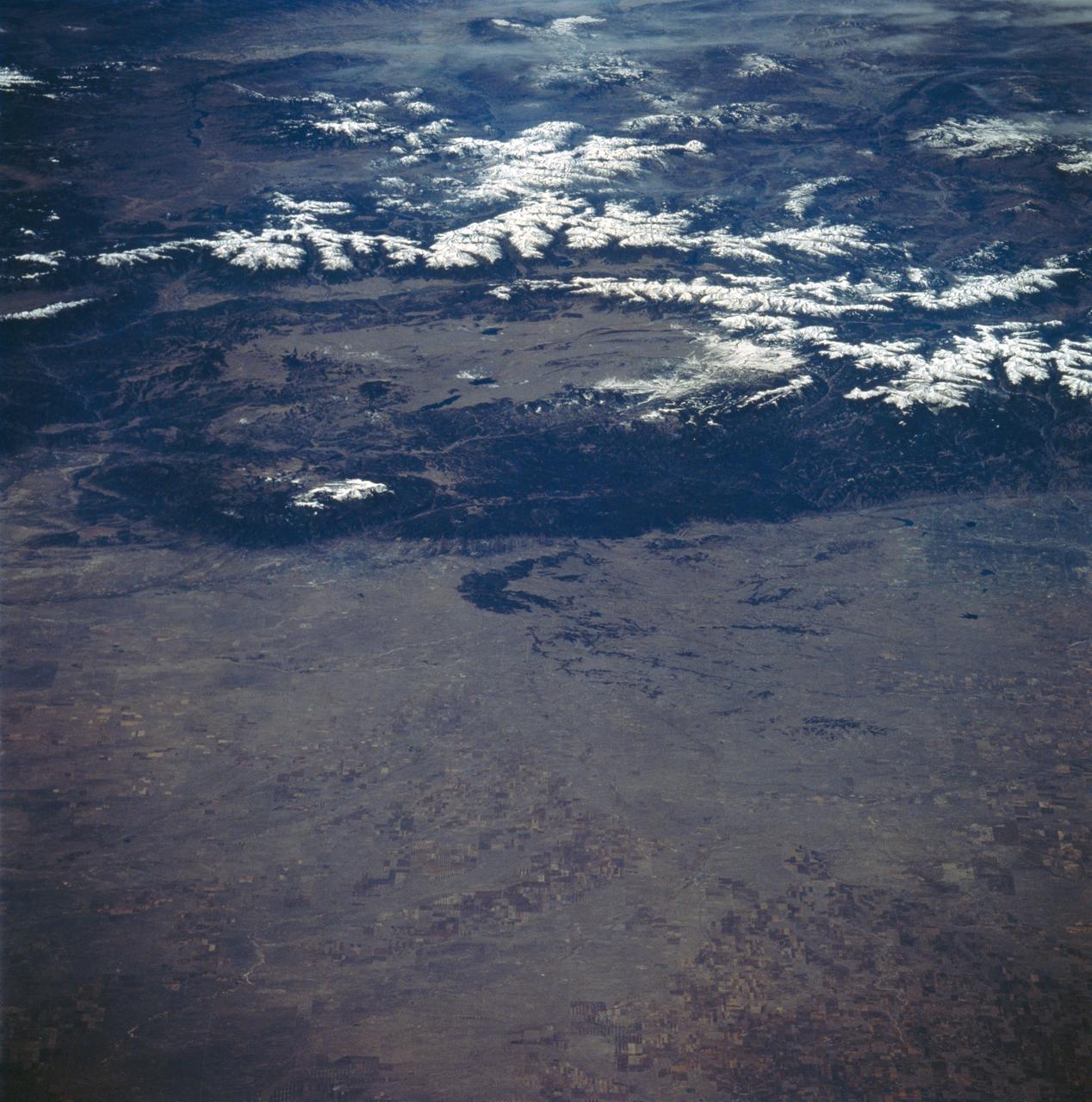STS058-89-013 (18 Oct-1 Nov 1993) --- An oblique westward view, across the wheat fields and cattle pastures, of eastern Colorado to the Front Range of the Rocky Mountains.  Denver is bisected at the center of the right edge of the frame.  Pikes Peak and Colorado Springs are left of center, and the Arkansas River Valley with Canyon City and the Royal Gorge are along the left edge of the frame.  This view shows the startling contrast between the nearly-flat High Plains and the ancient geological uplift of the Rockies.