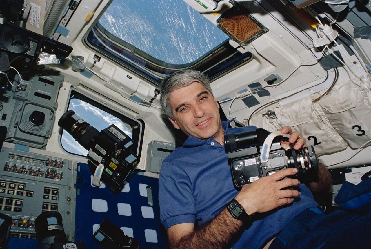 STS059-19-004 (9-20 April 1994) --- Astronaut Sidney M. Gutierrez, mission commander, pauses on the flight deck during Earth observations on the Space Shuttle Endeavour.  Gutierrez, who was joined by five other NASA astronauts for 11-days in Earth orbit, holds a 70mm Hasselblad camera.  The camera was one of several instruments used during the SRL mission to record an unprecedented compilation of data on planet Earth.