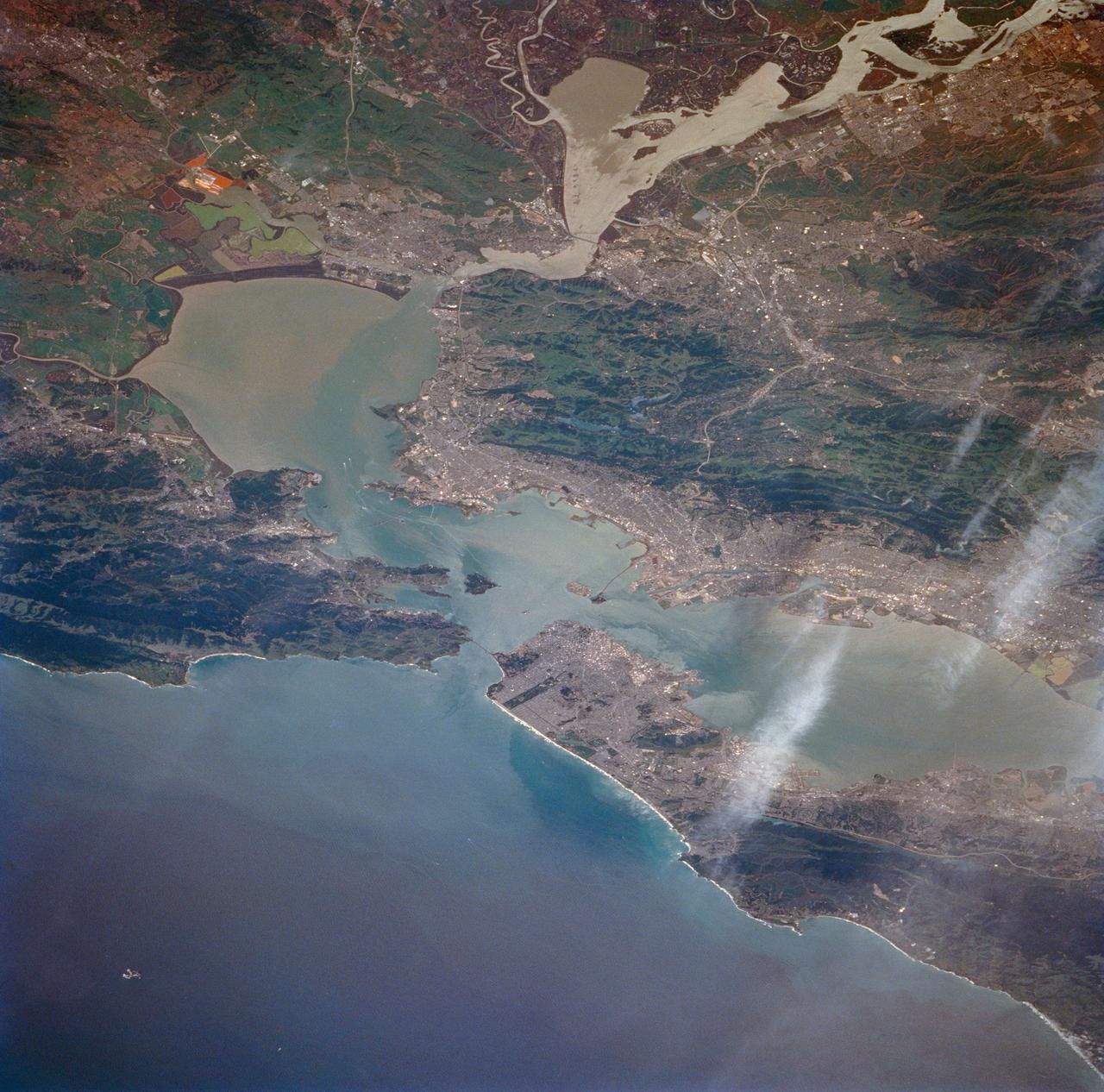 STS059-213-009 (9-20 April 1994) --- San Francisco Bay.  Orient with the sea up.  The delta of the combined Sacramento and San Joaquin Rivers occupies the foreground, San Francisco Bay the middle distance, and the Pacific Ocean the rest.  Variations in water color caused both by sediment load and by wind streaking strike the eye.  Man-made features dominate this scene.  The Lafayette/Concord complex is left of the bay head, Vallejo is to the right, the Berkeley/Oakland complex rims the shoreline of the main bay, and San Francisco fills the peninsula beyond.  Salt-evaporation ponds contain differently-colored algae depending on salinity.  The low altitude (less than 120 nautical miles) and unusually-clear air combine to provide unusually-strong green colors in this Spring scene.  Hasselblad camera.