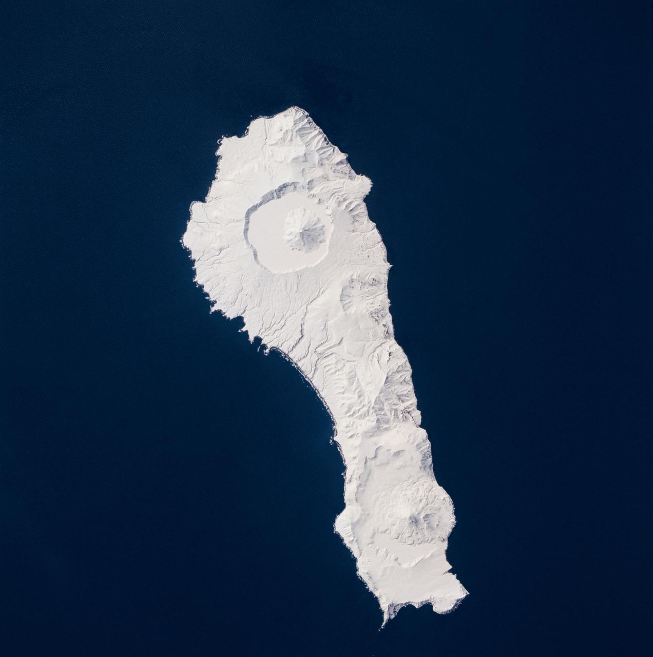 STS059-219-065 (9-20 April 1994) --- The narrow end of the island is to the north by northeast.  This is one of several volcanic islands extending south by southwest between the southern tip of Kamchatka and Japan.  The exposure was stopped down to provide extremely fine detail in the totally snow-covered landscape, at the same time making the dark sea look completely black.  Compare to STS047-90-087, taken in September, which shows a green ground cover.  Hasselblad photograph.