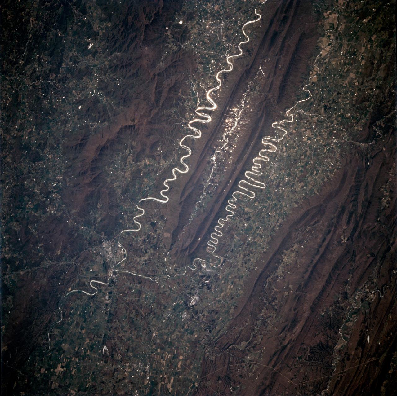 STS059-225-072 (9-20 April 1994) --- Orient with the tuning fork away from the viewer (sunglint is always south of the spacecraft at this latitude).  Then the South Fork (left) and North Fork (right) of the Shenandoah meet in the foreground; Front Royal, Virginia is just to the left of the combined rivers at the junction.  Massanutten Mountain, covered by reddish-brown fallen leaves of the George Washington National Forest, separates the river forks.  The mountain, and other elements of the Appalachian Mountains in this scene, were formed from folded sedimentary rocks that later were eroded into their present shapes; resistant rocks, such as sandstone, form the high ground while shale and limestone form the valleys.  Hasselblad photograph.