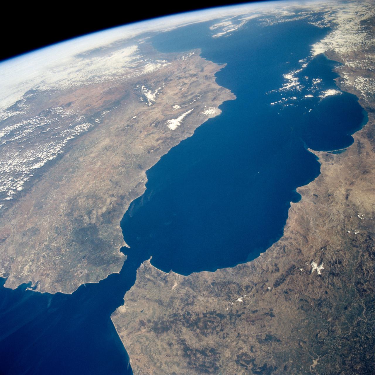 STS059-238-074 (9-20 April 1994) --- The Atlantic Ocean, Straits of Gibraltar, and Alboran Sea (the westernmost portion of the Mediterranean Sea) separate Spain on the left from Morocco on the right.  Algeciras Harbor is the prominent notch cut out of the eastern end of the north shore of the Strait; the Rock of Gibraltar is the tiny arrowhead that separates the notch from the Alboran Sea.  The Sierra Nevada, farther away down the Spanish coast, lives up to its name in this April scene.  The difference in elevation between the Sierra Morena and the Guadalquivir River valley is highlighted nicely by cumulus clouds.  Tangier, Morocco can be seen as a light-toned spot on the southern shore of the Strait, near the entrance to the Atlantic Ocean.  Hasselblad photograph.