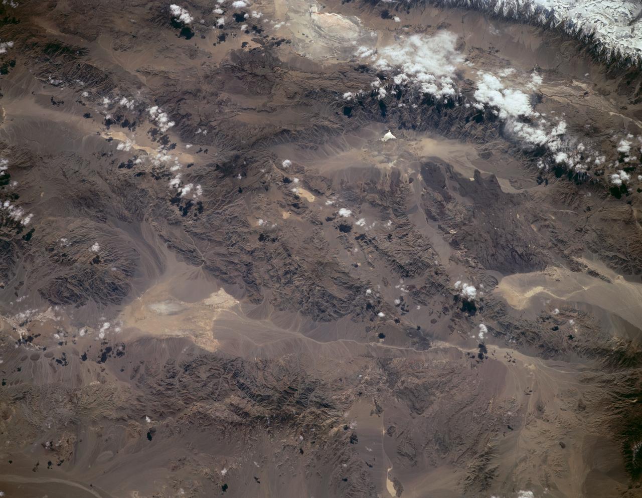 STS059-L09-162 (9-20 April 1994) --- Orient with the snow-covered mountains (Sierra Nevada of California) in the upper right corner. Then Owens Valley runs along the top of the photograph to Owens Lake playa at top center. The upper end of Death Valley extends from right to left in the foreground, with the drainage running down to a playa at Stovepipe Wells in the left foreground. Geologists are studying microwave signatures of the different playa surfaces, and the coatings on alluvial fans that extend from mountain masses, to try to sort out the history of different climates in this formerly wet but now hyperarid region.
