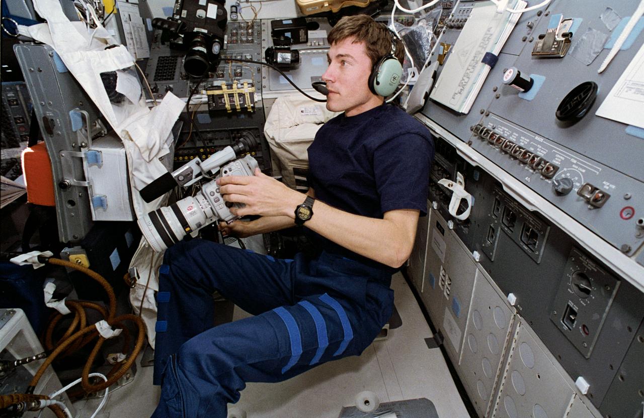 STS60-29-009 (10 Feb 1994) --- On the Space Shuttle Discovery's aft flight deck, Russian cosmonaut Sergei K. Krikalev prepares for one chore while performing another.  Using the Shuttle Amateur Radio Experiment (SAREX) gear, the mission specialist was talking with students in Maine.  He holds a camcorder, which was later called into action to record inflight activities.  Krikalev joined five NASA astronauts for eight days in space aboard Discovery.