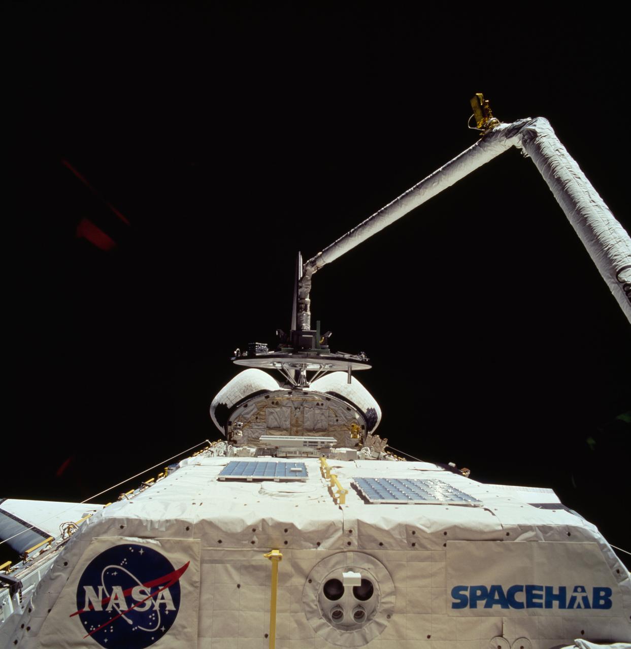 STS060-74-054 (3-11 Feb 1994) --- The Wake Shield Facility (WSF) is held in the grasp of Discovery's Remote Manipulator System (RMS).  The 70mm image, backdropped against the blackness of space, also shows the SPACEHAB module in the forward cargo area.