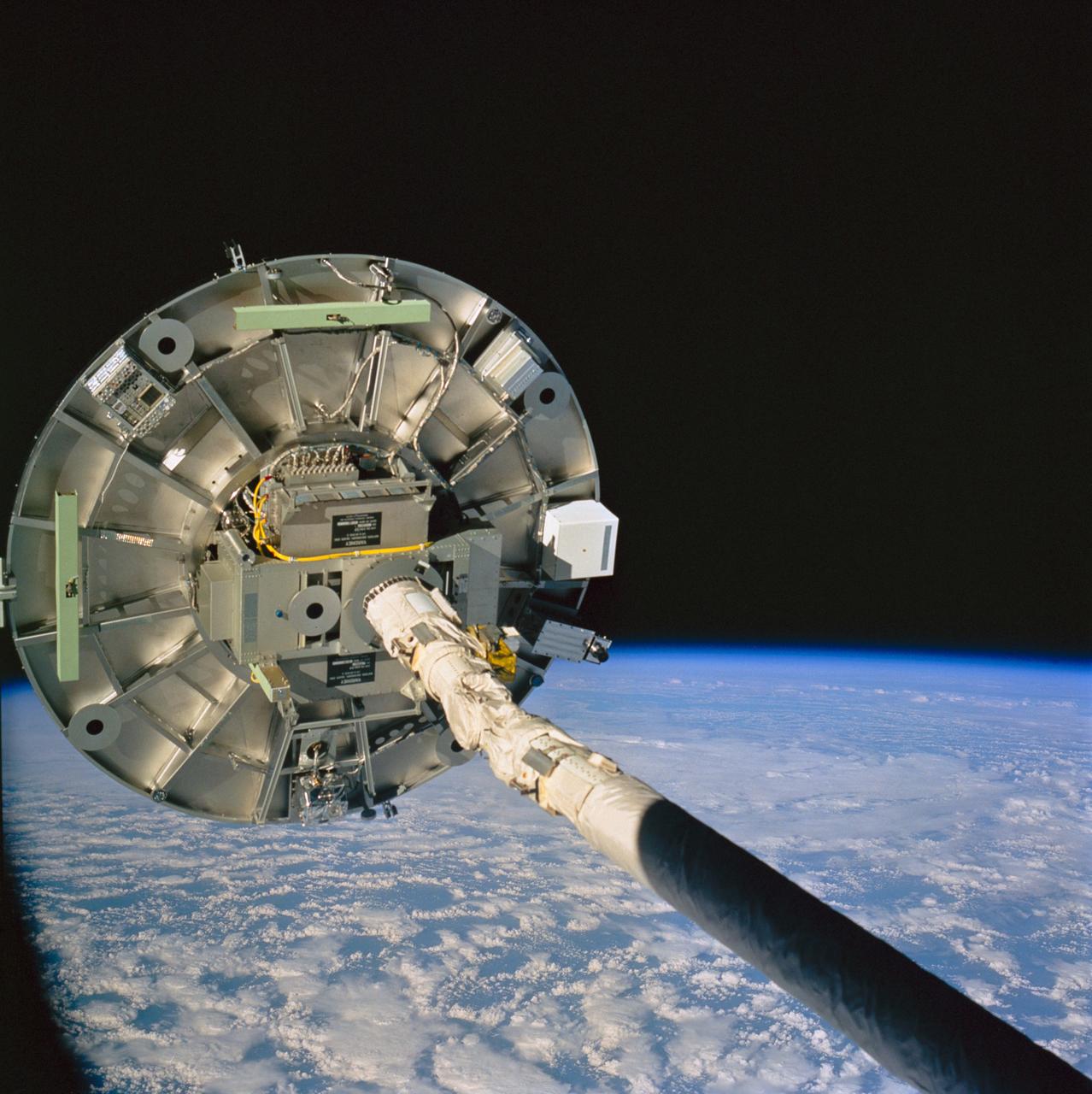STS060-76-095 (3-11 Feb 1994) --- The ram side of the Wake Shield Facility (WSF) in the grasp of the Space Shuttle Discovery's Remote Manipulator System (RMS) arm is featured in this 70mm frame.  Clouds over the Atlantic Ocean and the blackness of space share the backdrop for the picture.  Five NASA astronauts and a Russian cosmonaut spent eight days in Earth orbit in support of the STS-60 mission.