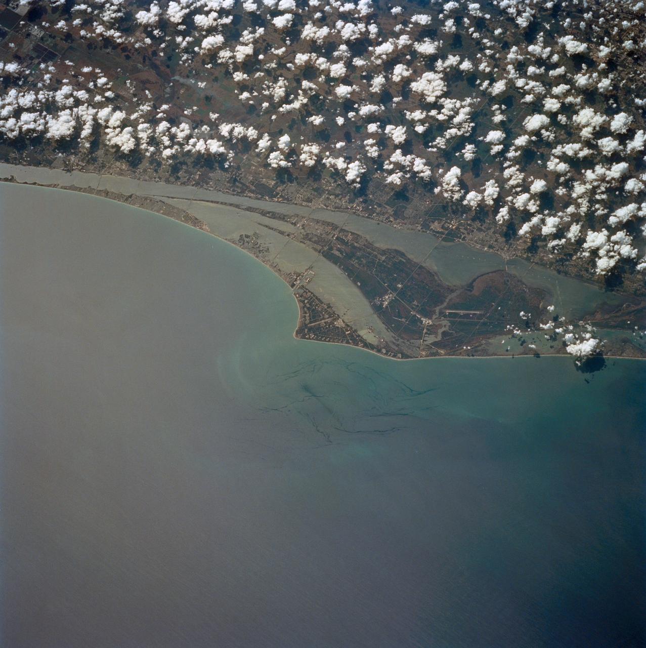 STS060-84-021 (3-11 Feb 1994) --- The Kennedy Space Center (KSC) and its partially cloud-covered environs were captured on 70mm by one of the STS-60 crew members during the eight-day mission. The Shuttle landing facility, on which Discovery landed February 11, 1994, visible at left center.