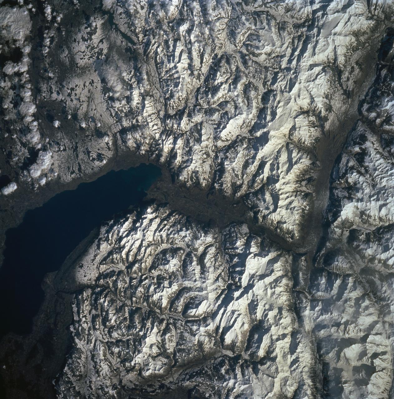 STS060-90-007 (3-11 Feb 1994) --- Parts of the Swiss Cantons of Vaud and Valois and the French province of Chablais are shown.  These mountains were created in the last great mountain-building episode in Europe around 50 million years ago.  They have been reshaped by glaciers during the Pleistocene.  The glaciers created the wide valley of the Rhone River by scouring a pre-existing stream.  The fertile Swiss Plateau runs northwest from the shore of Lake Geneva and is visible in the upper right.  The Franco-Swiss border is located in the center of the lake and follows a mountain divide east of the Rhone Valley.  According to NASA geologists eutrofication is a problem in Lake Geneva.  In 1971 a Swiss Commission was formed to try to slow the problem.  Strong discharge laws were enacted, but  they are hard to enforce due to the multi-national and multi-organizational parties contributing to the problem.