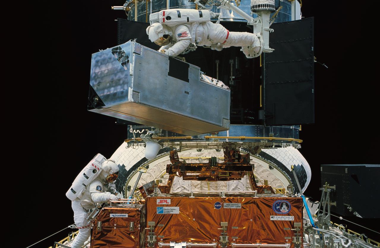 STS061-47-014 (8 Dec 1993) --- Astronaut Kathryn C. Thornton lifts the Corrective Optics Space Telescope Axial Replacement (COSTAR) prior to its installation on the Hubble Space Telescope (HST).  Thornton is anchored to a foot restraint on the end of the Remote Manipulator System (RMS) arm.  Astronaut Thomas D. Akers, who assisted in the COSTAR installation, is at lower left.