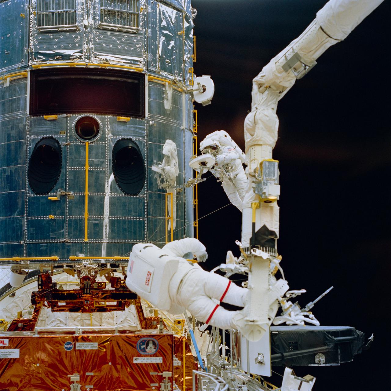 STS061-74-046 (7 Dec 1993) --- Anchored on the end of the Space Shuttle Endeavour's Remote Manipulator System (RMS) arm, astronaut Jeffrey A. Hoffman (foreground) prepares to install the new Wide Field\Planetary Camera (WFPC II) into the empty cavity (top left) on the Hubble Space Telescope (HST).  WFPC I is seen temporarily stowed at bottom right.  Astronaut F. Story Musgrave works with a Portable Foot Restraint (PFR) at frame center, as his image is reflected in the shiny surface of the telescope.  Hoffman and Musgrave shared chores on three of the five extravehicular activity?s (EVA) during the mission.