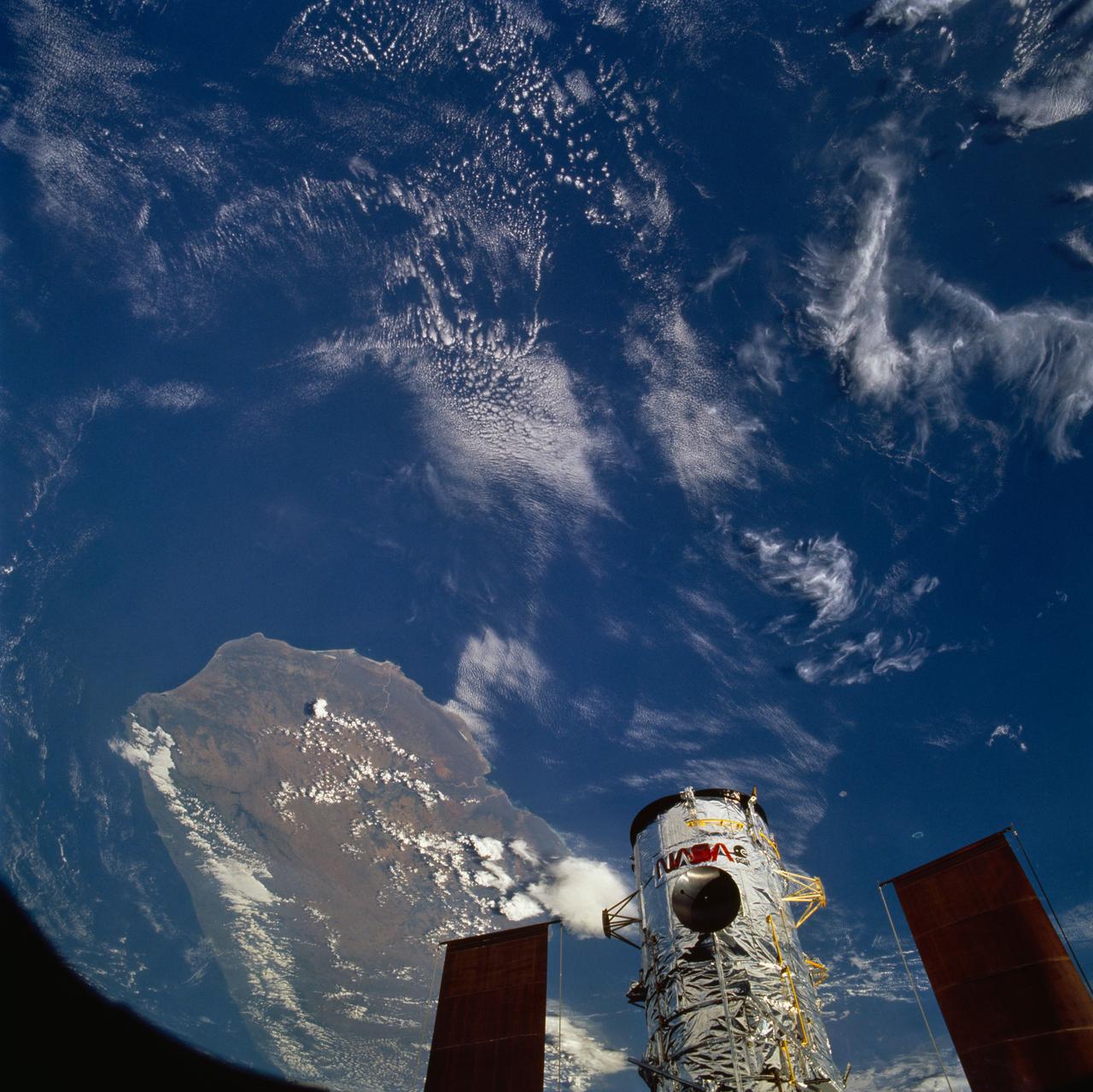 STS061-79-086 (4 Dec 1993) --- The Hubble Space Telescope (HST), backdropped over Madagascar, is berthed in the Space Shuttle Endeavour's cargo bay following its capture by the STS-61 astronauts.  The crew used TV cameras to survey the spacecraft before sending out four astronauts on five separate sessions of extravehicular activity (EVA) to perform a variety of servicing tasks.