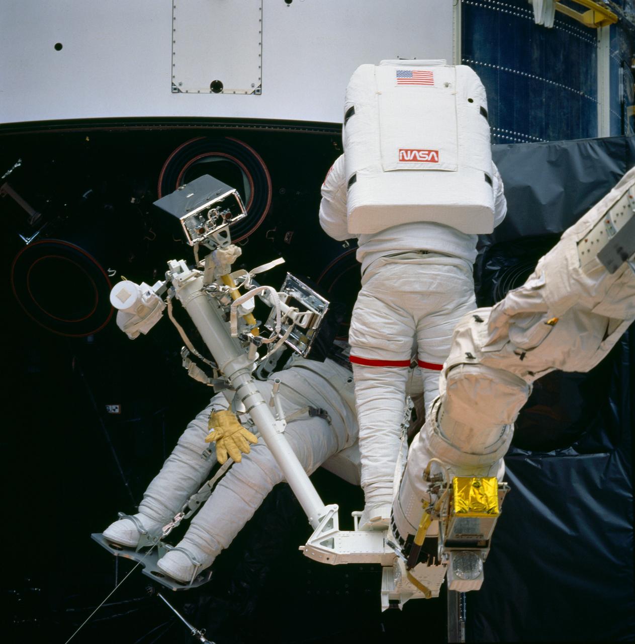STS061-87-046 (5 Dec 1993) --- Astronauts Jeffrey A. Hoffman (right) and F. Story Musgrave work near the base of the Hubble Space Telescope (HST) on the first of five spacewalks.  Their particular mission here is to replace failed Rate Sensor Units (RSU) inside the telescope's housing.  Hoffman is anchored to a foot restraint, mounted on the end of the Space Shuttle Endeavour's Remote Manipulator System (RMS) arm, while Musgrave is standing on a foot restraint attached to a support structure in the cargo bay.
