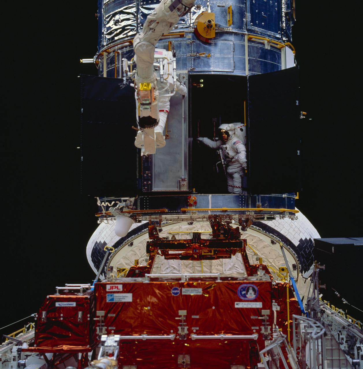 STS061-94-050 (8 Dec 1993) --- Astronaut Thomas D. Akers maneuvers inside the bay which will house the Corrective Optics Space Telescope Axial Replacement (COSTAR) while assisting astronaut Kathryn C. Thornton with the installation of the 640-pound instrument.  Thornton, anchored on the end of the Remote Manipulator System (RMS) arm, is partially visible as she prepares to install the COSTAR, during their extravehicular activity (EVA).