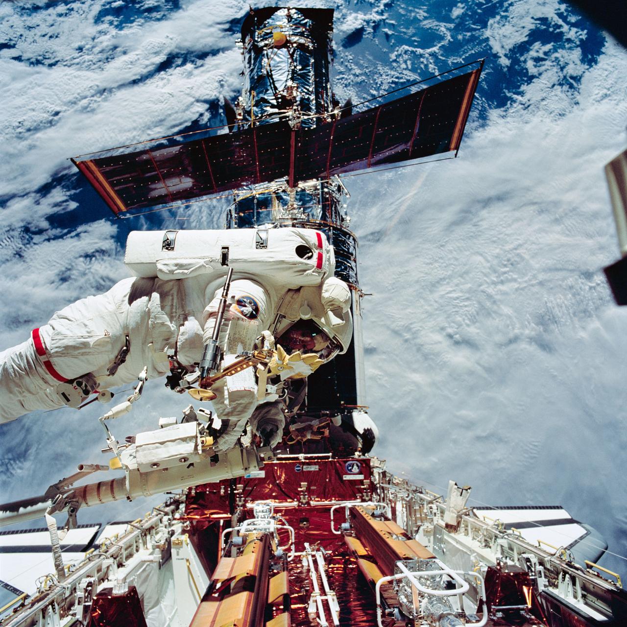 STS061-95-028 (6 Dec 1993) --- Astronaut Kathryn C. Thornton, on the end of the Space Shuttle Endeavour's Remote Manipulator System (RMS) arm, hovers over equipment associated with servicing chores on the Hubble Space Telescope (HST) during the second extravehicular activity (EVA) on the eleven-day mission.  Astronauts Thornton and Thomas D. Akers changed out the solar array panels during this EVA.