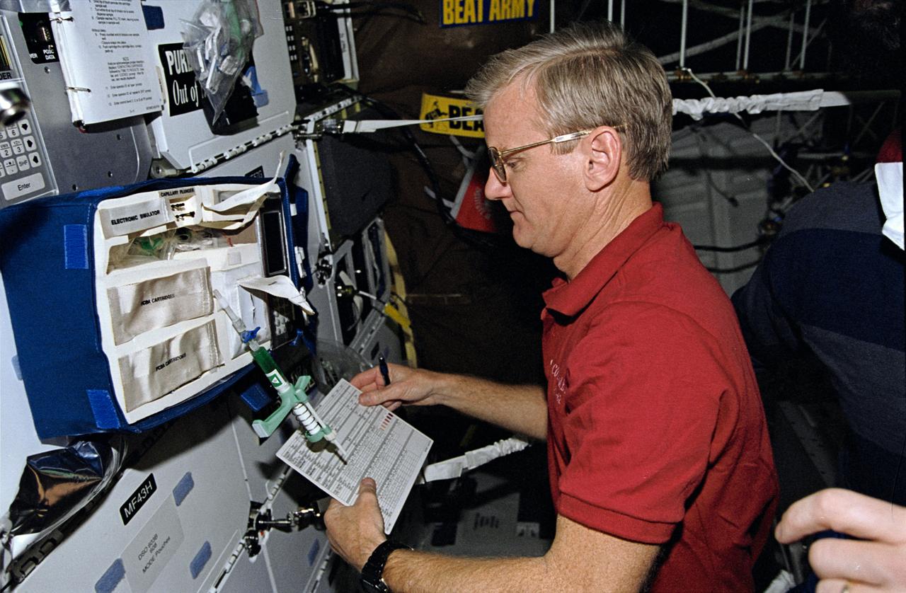 STS062-10-010 (4-18 March 1994) --- Astronaut John H. Casper, mission commander, takes stock of paraphenalia used to support medical testing onboard Columbia's middeck.  Casper was poind by four other veteran astronauts for 14 days of variegated research in earth orbit.