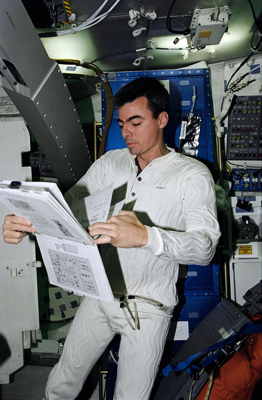STS062-12-015 (4-18 March 1994) --- On Coumbia's middeck, astronaut Andrew M. Allen, pilot, looks over a procedures book in the midst of a 14-day mission. Allen is attired in a new thermally controlled undergarment. As part of a detailed test objective, both Allen and John H. Casper, mission commander, wore the undergarments during the launch and entry phases of the flight.