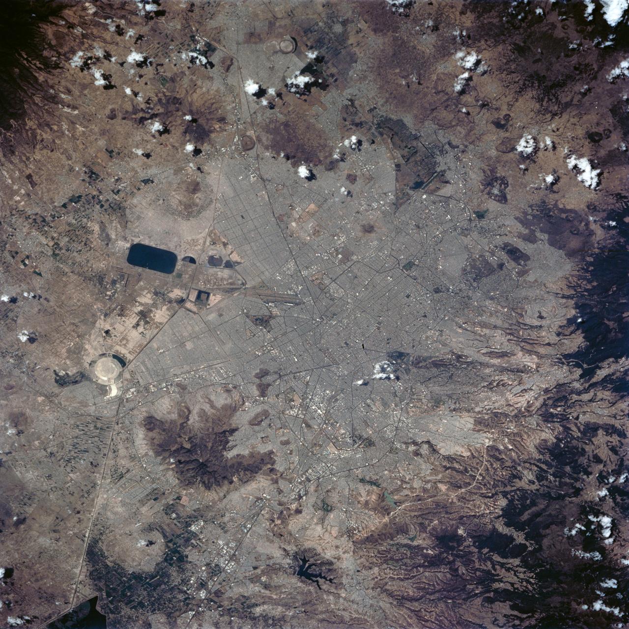 STS062-84-028 (4-18 March 1994) --- According to NASA scientists this image is the clearest photo of Mexico City taken from United States manned spacecraft. North is to the upper right. Mexico City sits in a basin surrounded by large volcanoes. The restricted atmospheric circulation in the basin, coupled with the inevitable air emissions produced by a city of 20 million people has created a critical air pollution problem for the city. In most photographs of the region, Mexico City is obscured by haze. Scientists feel the clear atmosphere in this photograph may be due, in part, to the stringent air emission restrictions now in place. The clarity of the photograph allows many key cultural features to be identified, including all of the major boulevards, the horse track (western part of the city), the university (south of the city), and the museum areas. Large, man-made ponds east of the city also stand out.
