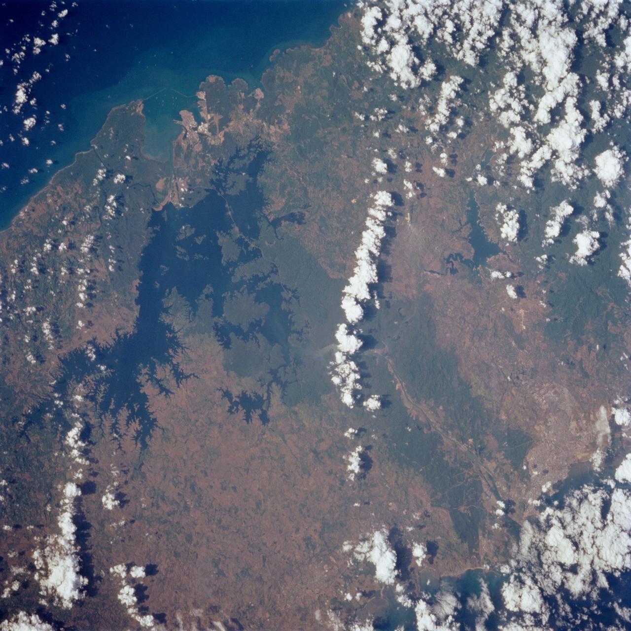 STS062-85-095 (4-18 March 1994) --- Gatun Lake and the forested Panama Canal Zone can be seen in this north northwest-looking low oblique photograph obtained in March 1994.  The shipping chanel of the canal is 82.4 kilometers (51.2 miles) long, though the canal zone is only 65 kilometers (40 miles) long.  The width of the canal zones extends generally 8 kilometers (5 miles) on either side of the shipping channel, except near Madden Lake.  The canal connects the Atlantic Ocean (coastal city of Colon) with the Pacific Ocean near Panama City in a line that takes a northwest to southeast course because of the configuration of the isthmus.  The canal zigzags across the isthmus to take advantage of the geographic features of the area such as the Chagres River.  The controlled water supply for the canal is provided by the three artificial lakes: Gatun near the Atlantic terminus, Miraflores near the Pacific terminus and Madden about halfway across the isthmus.  Gatun is the largest of the three lakes covering an area of 429 square kilometers (165 square miles).  In the midst of this lake is Barro Colorado Island, a world-famous wild game perserve.  Madden Lake was built as a large supplemental reservoir to keep water levels up in the canal during the dry season.  All three lakes are vital sources of water for maintaining the ship channel over the continental divide (Gaillard Cut) and for regulating the flow of water that enables hugh vessels to be lifted and lowered in massive locks.