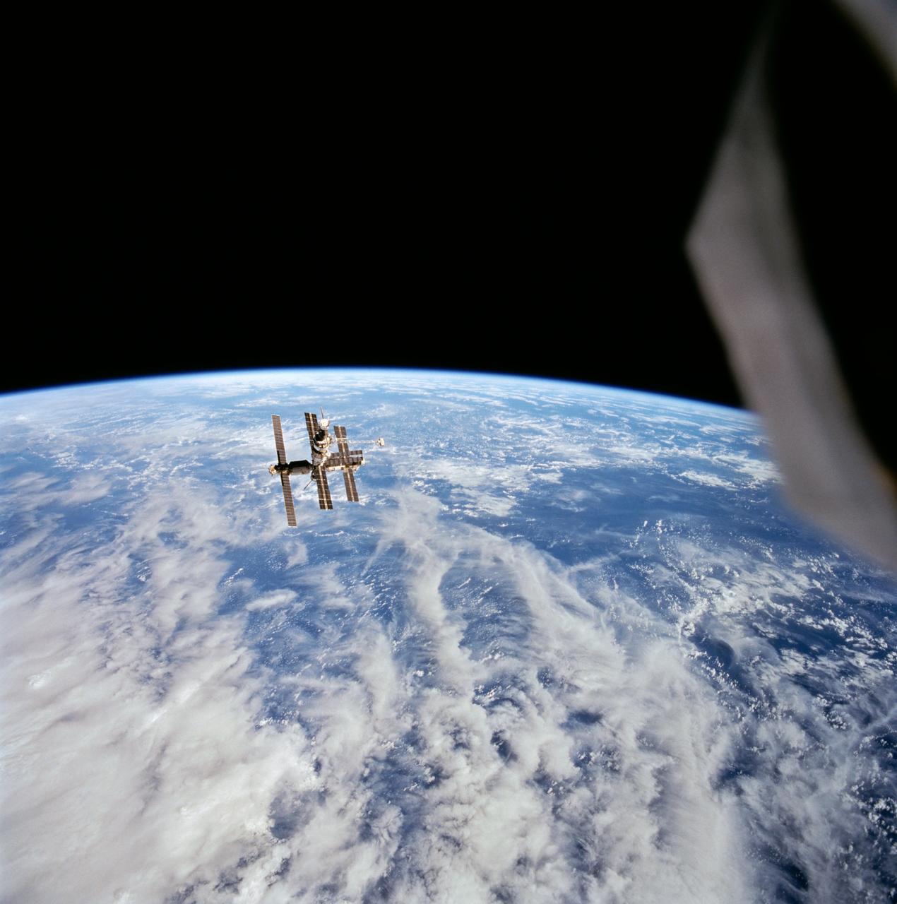 STS063-708-095 (6 Feb 1995) --- Cumulus and other clouds over the ocean form the backdrop for this scene of Russia's Mir space station during rendezvous operations by the Space Shuttle Discovery and Mir.  This photograph was taken as the Discovery was firing its Reaction Control Subsystem (RCS) thrusters to separate from Mir's proximity.  Onboard the Discovery were astronauts James D. Wetherbee, mission commander; Eileen M. Collins, pilot; Bernard A. Harris Jr., payload commander; mission specialists Janice Voss and C. Michael Foale; along with Russian cosmonaut Vladimir G. Titov.        EDITOR'S NOTE: This 70mm handheld Hasselblad frame has been cropped to enlarge Mir.
