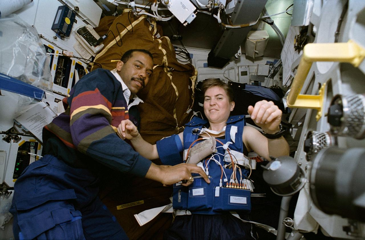 STS063-86-016 (3-11 Feb 1995) --- With astronaut Janice E. Voss, mission specialist, as his test subject, astronaut Bernard A. Harris, Jr., payload commander and a physician, uses a special biomedical harness experiment to check the response of muscles to microgravity.  They are on the mid-deck, where many of the SpaceHab 3 experiments are located.  The SpaceHab 3 Module is in the cargo bay.  Others onboard the Space Shuttle Discovery were astronauts James D. Wetherbee, commander; Eileen M. Collins, pilot; mission specialists C. Michael Foale and Russian cosmonaut Vladimir G. Titov.